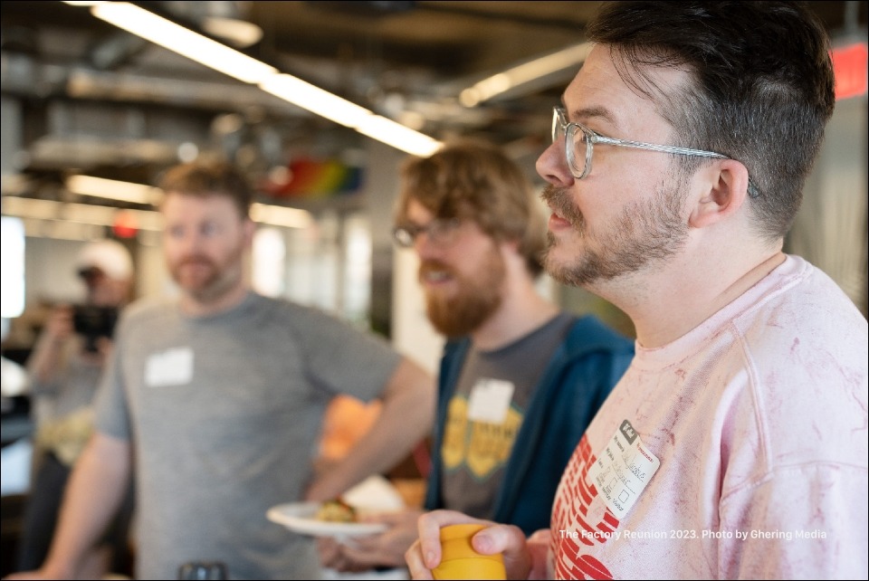 A Factory member leading a conversation while two other Factory members stand adjacent.