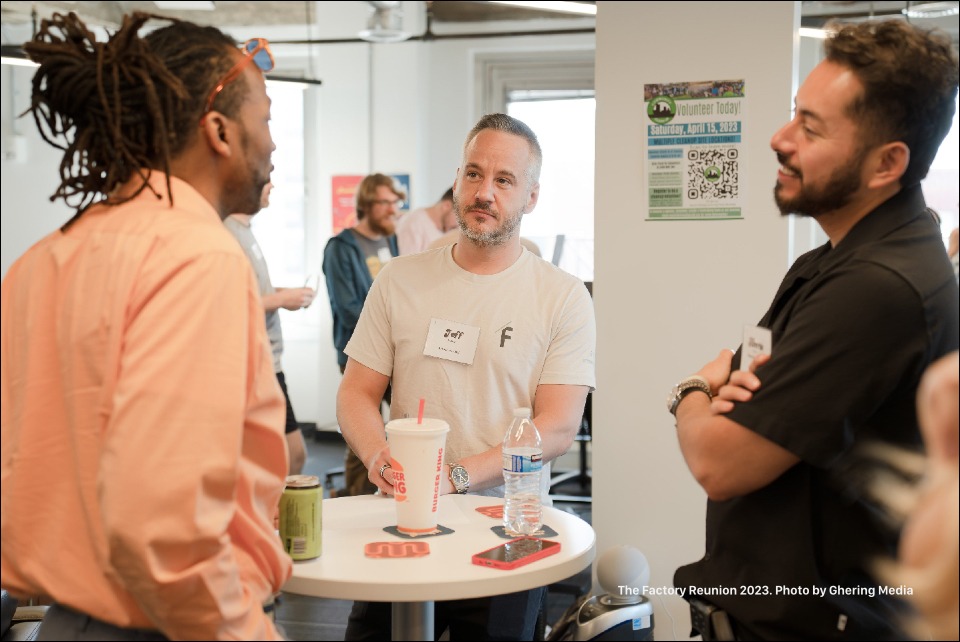 Three of our Factory community members standing around a table having a talk.