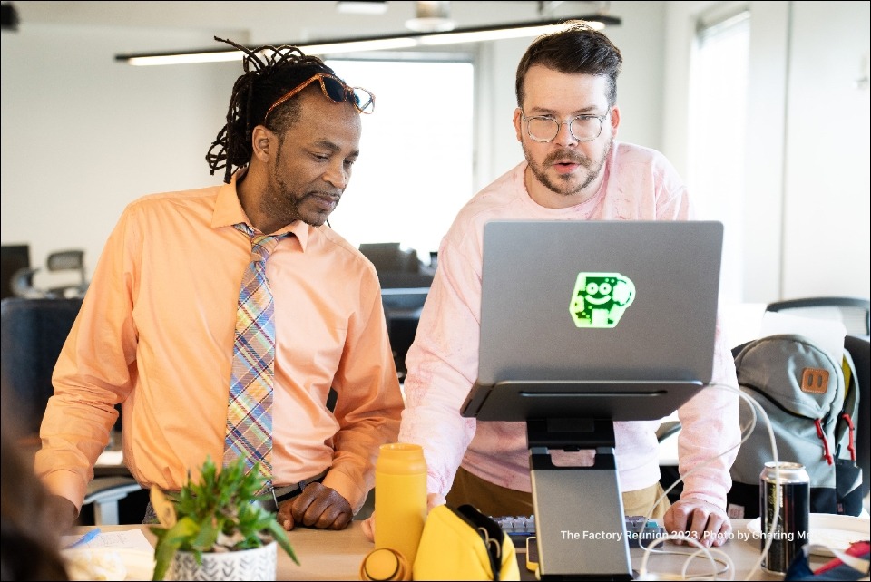 Two Factory members looking at a laptop computer screen.