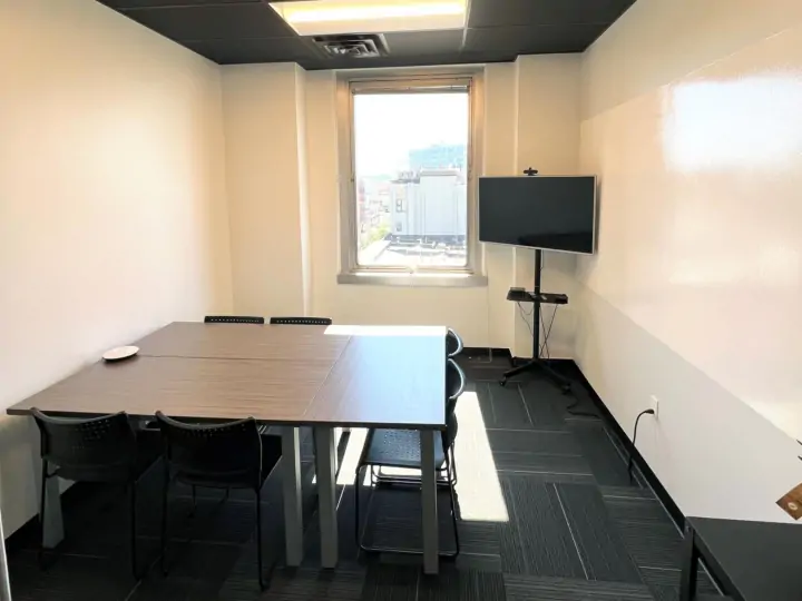 Our Eastown conference room with 3 tables and tv next to a white board wall