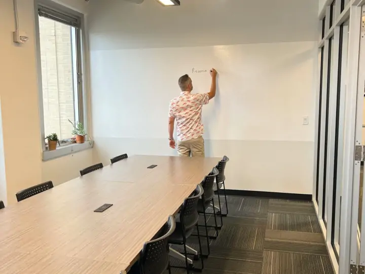 Man writing on the white board wall in the Learning Center conference room