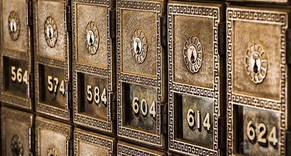 Close up photo of old style brass mail boxes with numbers 584, 604, and 614 on each of the mail box windows.